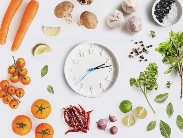 Suivre un régime et une alimentation saine. Cadre d'horloge avec ingrédient alimentaire, légumes et herbes