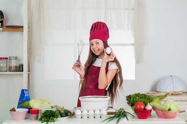 Suivre un régime. enfance heureuse. un enfant heureux porte un uniforme de cuisinier. fille de chef en chapeau et tablier. enfant cuisiner des aliments dans la cuisine. Choisir une carrière. petite aide avec batteur et oeuf. culinaire et gastronomique.