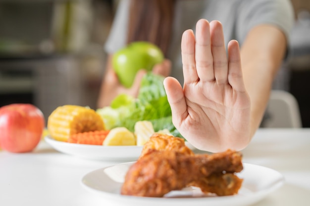 Suivre un régime jeune femme ou fille asiatique repousser la malbouffe au poulet frit et choisir la salade de légumes aux pommes vertes manger de la nourriture pour une bonne santé lorsqu'elle a faim Personne de perte de poids féminine