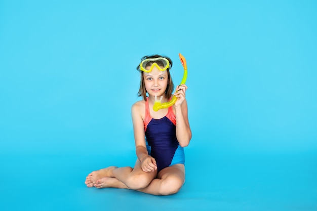 Sujet de vacances: enfant fille avec équipement de plongée en apnée ou de plongée sur un mur bleu. Concept d'aventure et de repos