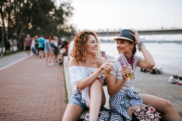 Summertime fun. Des filles profitant d&#39;un verre près de la rivière dans la ville.