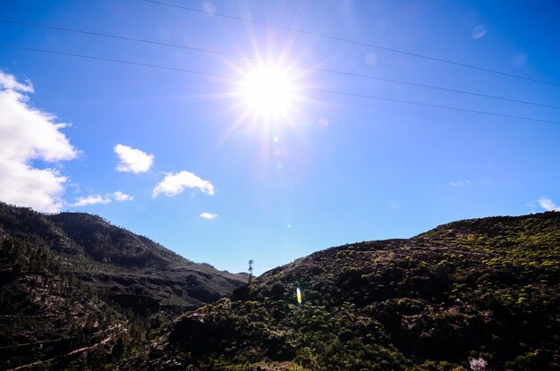 Sun Star sur un ciel bleu au-dessus d'une silhouette de montagne