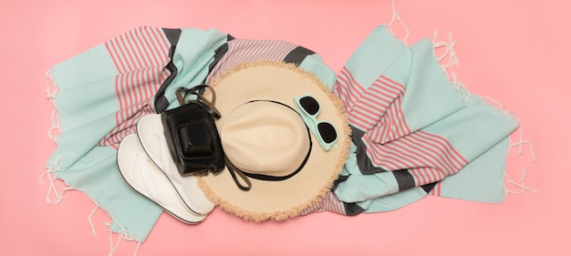 Sunhat et lunettes de soleil sur la plage de paille rose percutant avec un espace pour le texte.