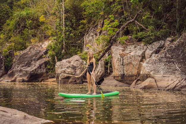 SUP Stand up paddle board femme paddle board sur le lac debout heureux sur paddleboard sur l'eau bleue Photo d'action de jeune femme sur Paddle Board