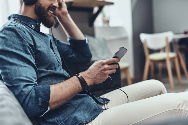 Super chanson ! Gros plan sur un jeune homme tenant un téléphone portable et écoutant de la musique