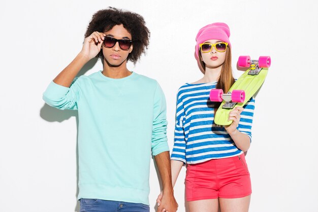 Super style et amoureux. Funky jeune couple portant des lunettes et posant sur fond blanc