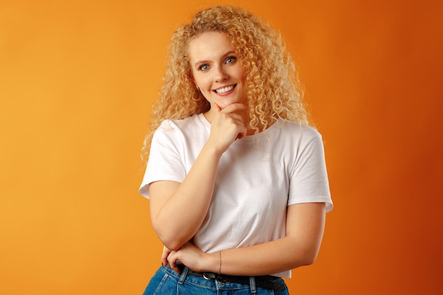 Superbe belle jeune femme aux cheveux bouclés posant à la caméra se bouchent