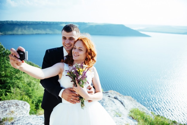 Superbe blonde mariée et le marié chic sur les rochers, au milieu de la mer