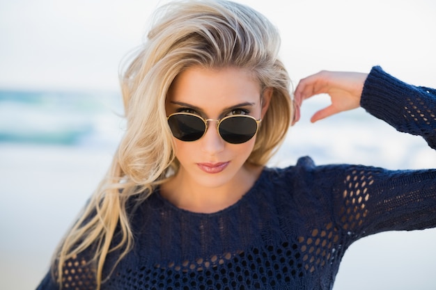 Superbe blonde sensuelle regardant par-dessus ses lunettes de soleil