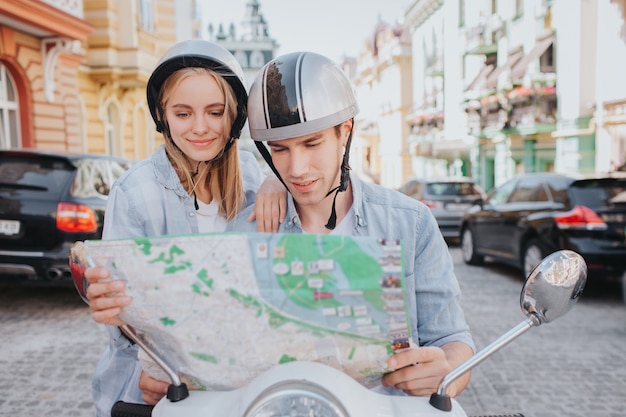 Superbe couple monté sur une moto dans la ville et à la recherche d'une carte