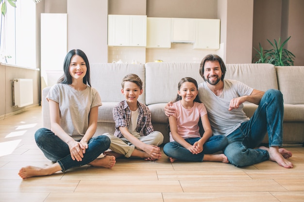 Superbe famille sont assis sur le sol avec leurs jambes maculées et regardant la caméra