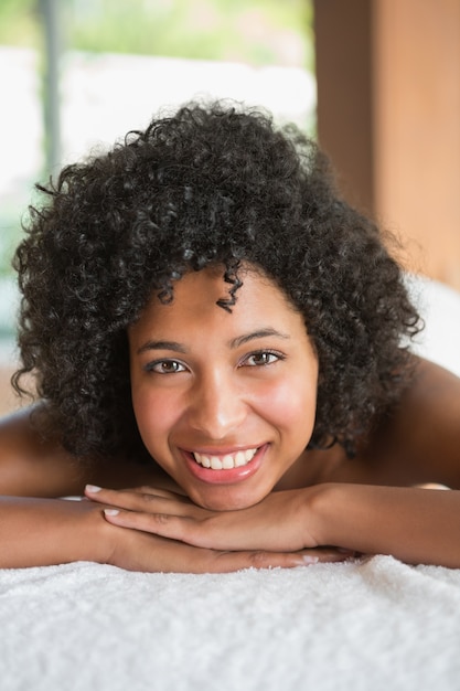 Superbe femme allongée sur la table de massage, souriant à la caméra