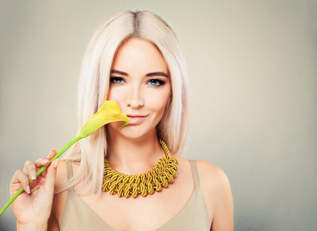 Superbe femme aux cheveux blonds. Maquillage, fleur et coiffure blonde