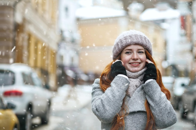 Superbe femme aux cheveux rouges marchant dans la rue pendant les vacances de Noël. Espace pour le texte