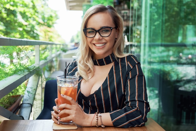 Photo superbe femme blonde aux cheveux ondulés reposant sur le café terr