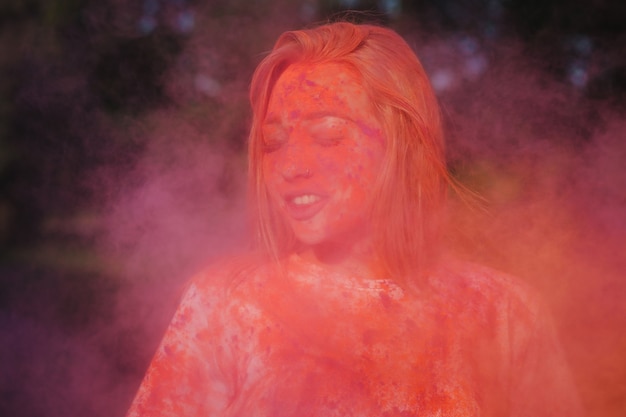 Photo superbe femme blonde caucasienne posant avec de la peinture rose qui explose au festival holi