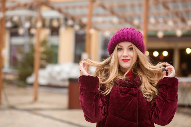 Superbe femme blonde portant des vêtements d'hiver chauds, posant sur le fond des lumières