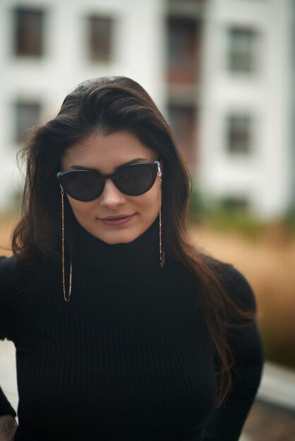 Une superbe femme brune porte des lunettes de soleil avec des chaînes de lunettes de soleil