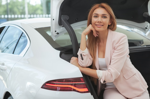 Superbe femme choisissant une nouvelle voiture chez le concessionnaire