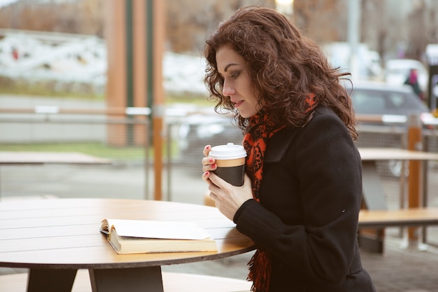 Superbe Femme Lisant Attentivement Un Livre Avec Une Tasse De Boisson Chaude