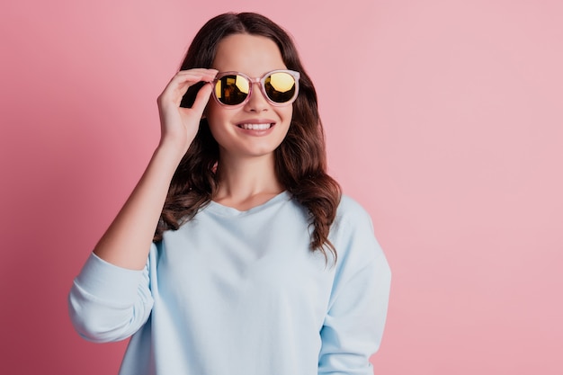 Superbe femme magnifique posant en lunettes de soleil sur fond rose