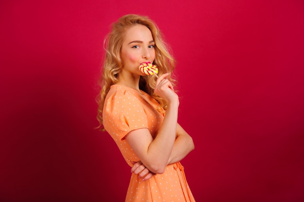 Superbe jeune blonde posant sur un mur lumineux