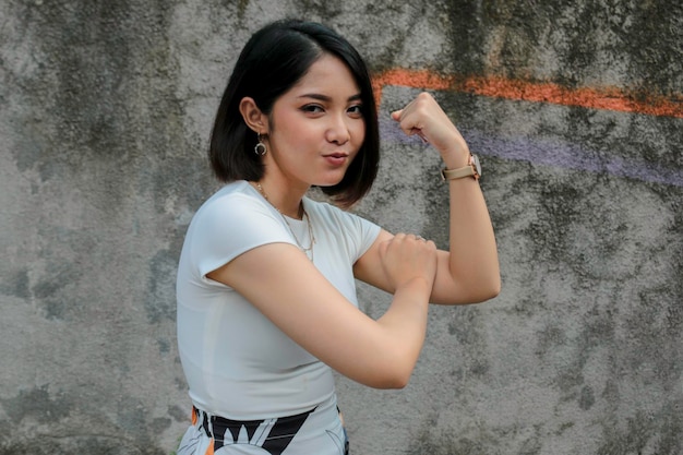 Superbe jeune femme asiatique forte avec une chemise blanche montrant des biceps et un concept fort de fille indonésienne souriante