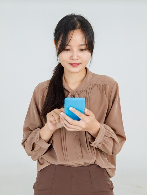 Superbe jeune femme asiatique pointant joyeusement le doigt vers l'écran du téléphone tout en vérifiant le téléphone portable pour obtenir des informations en ligne et de bonnes nouvelles.