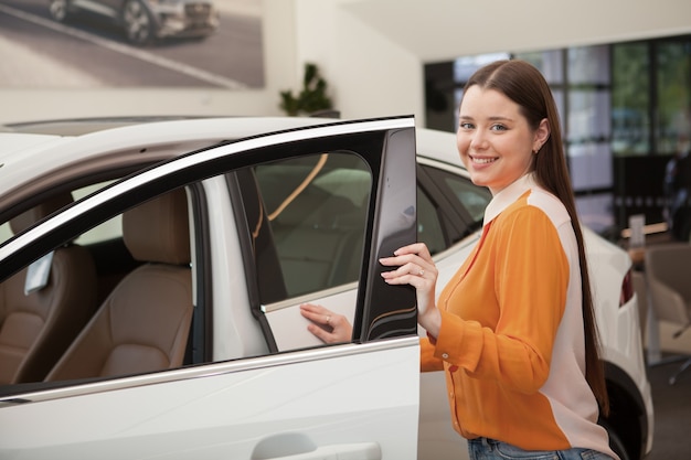 Superbe jeune femme heureuse achetant une nouvelle voiture chez le concessionnaire, espace de copie