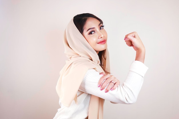 Superbe jeune femme musulmane forte isolée sur un mur de fond blanc montrant des biceps