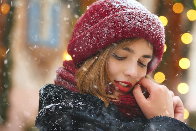 Superbe jeune femme profitant des chutes de neige pendant les vacances de Noël. Espace pour le texte