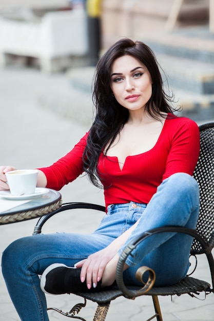 Superbe jeune femme avec une tasse de café dans la rue de la ville