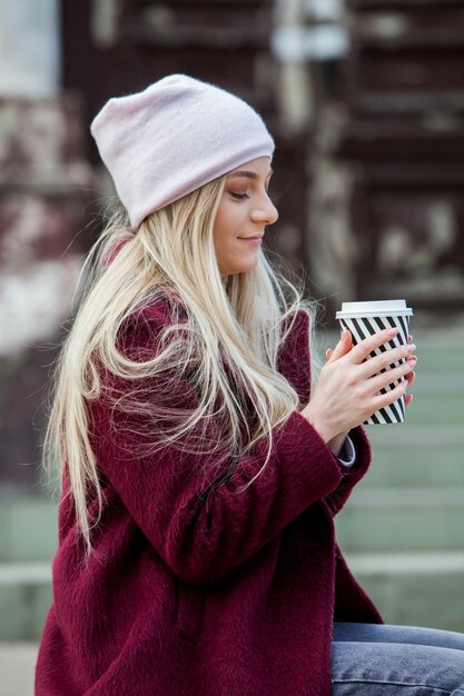 Superbe jeune femme avec une tasse de café dans la rue de la ville