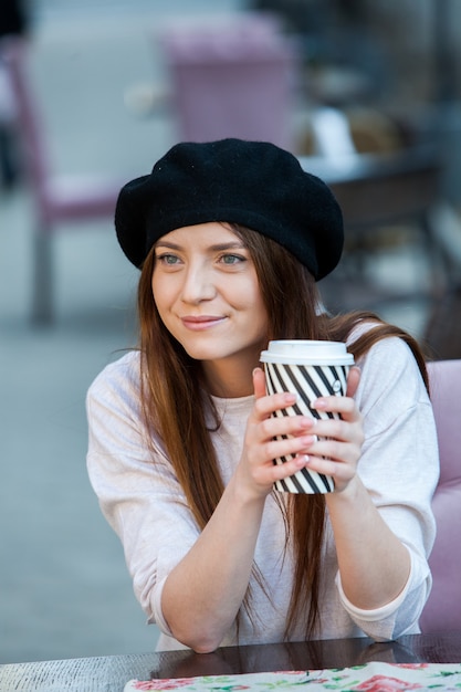 Superbe jeune femme avec une tasse de café dans la rue de la ville