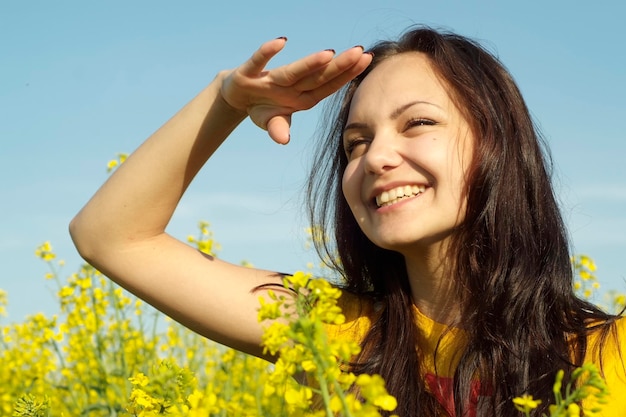 Superbe jeune fille au milieu d'un champ de fleurs jaunes