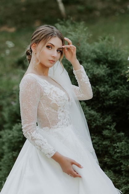 Superbe mariée élégante en robe blanche vintage marchant dans le parc