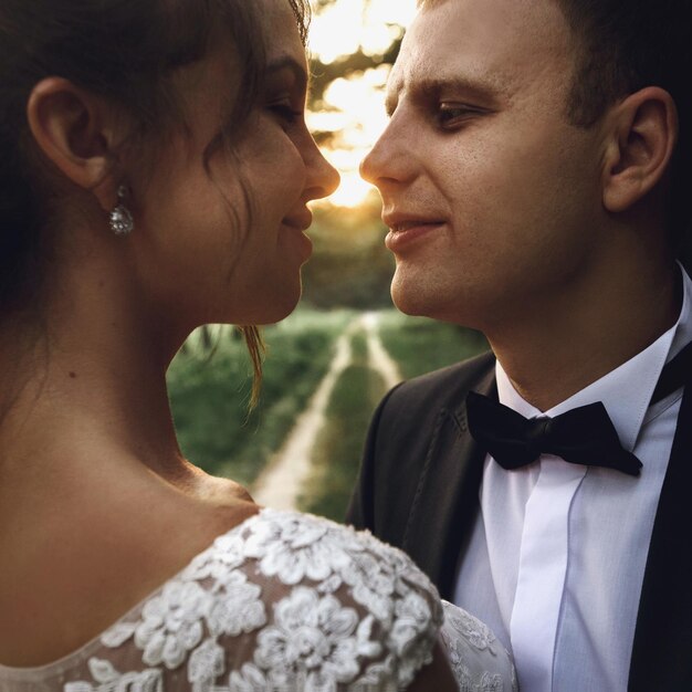 Photo superbe mariée heureuse élégante et marié élégant sur fond de beau coucher de soleil dans la forêt