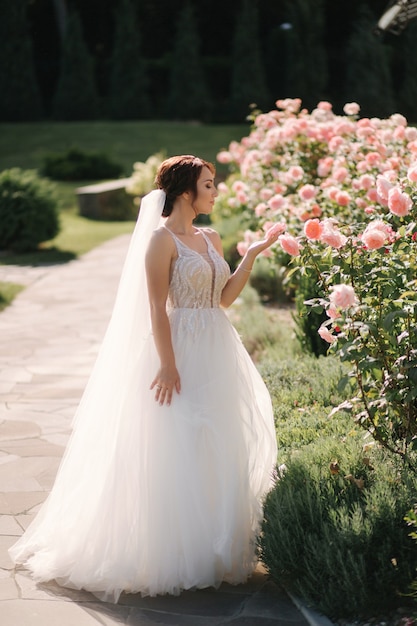 Superbe mariée en robe élégante à l'extérieur. Mannequin de fleurs roses