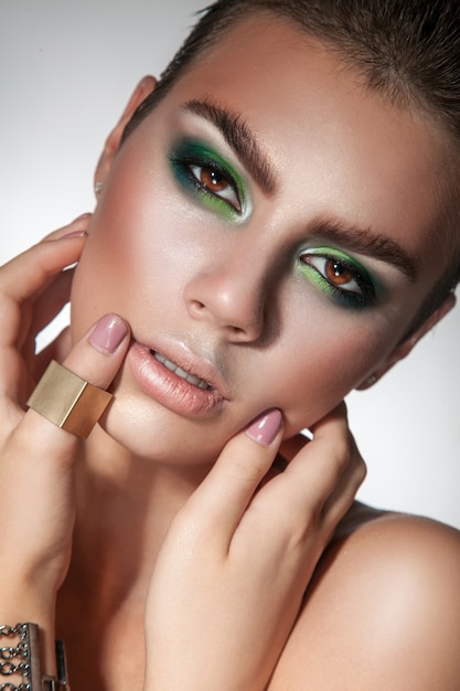 Photo superbe modèle avec une peau saine et un maquillage cool en regardant la caméra en studio de près