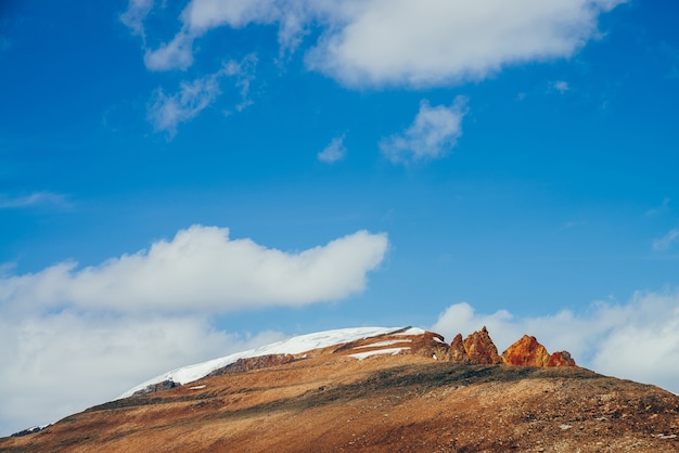 Superbe montagne ensoleillée avec des rochers bruns orange rouge en haut sous le ciel bleu