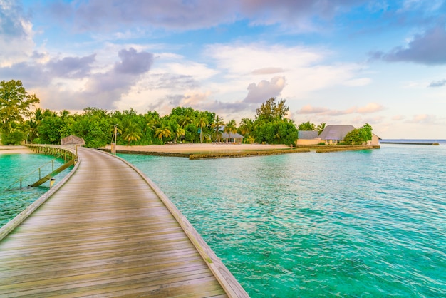 Superbes villas sur l&#39;eau dans l&#39;île tropicale des Maldives au moment du coucher du soleil.