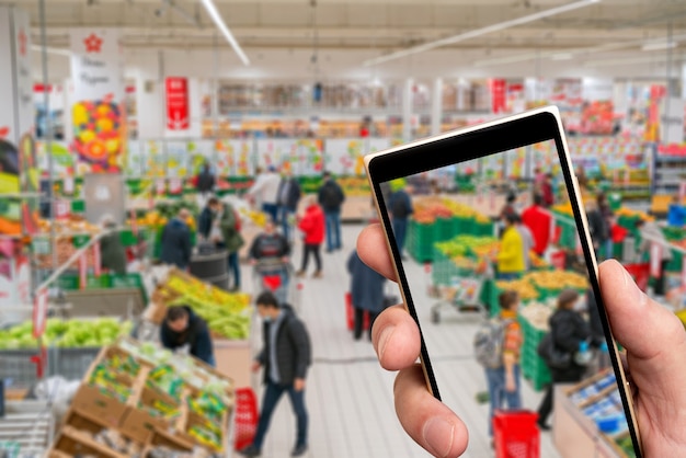 Supermarché flou et personnes faisant du shopping sur l'écran du smartphone