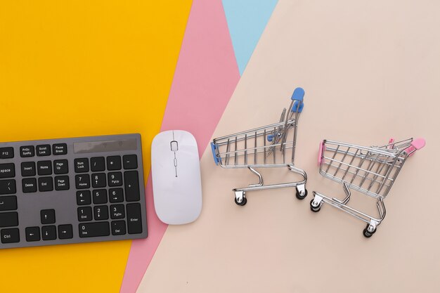 Supermarché en ligne. Clavier PC et caddie sur table colorée