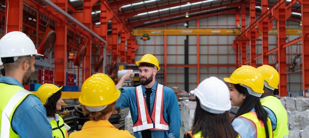 Le superviseur et un groupe d'ouvriers de l'usine portant des casques de sécurité se réunissent pour un briefing.