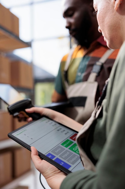 Les superviseurs de l'entrepôt analysent l'inventaire des marchandises sur les appareils numériques, préparent les commandes des clients avant de commencer à expédier les colis. Divers employés travaillant dans l'entrepôt. Photo en gros plan