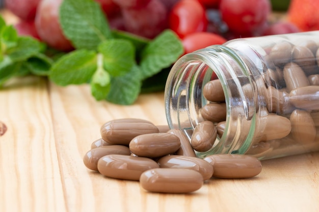 Suppléments de vitamines brunes sur la table en bois avec des fruits variés