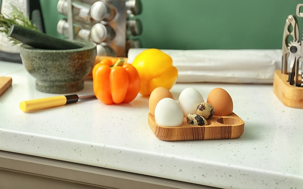 Support en bois avec des oeufs de poule sur table de cuisine