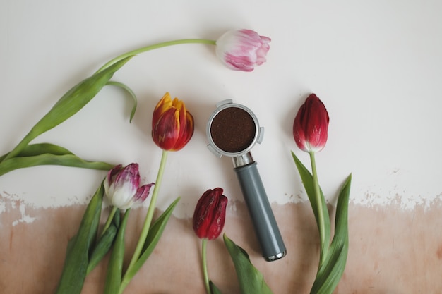 Support à café de la machine à café et tulipes fraîches sur fond blanc