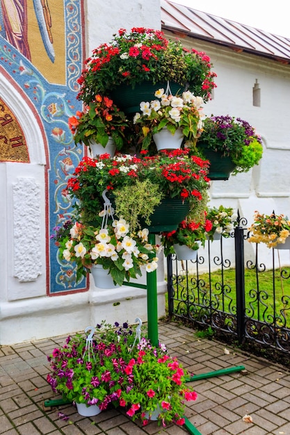 Support en fer avec de nombreux pots de fleurs avec différentes fleurs épanouies