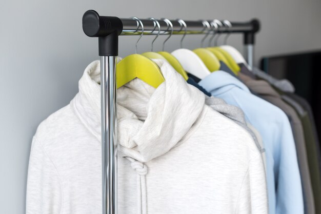 Support de suspension avec des vêtements chauds de printemps ou d'automne sur fond gris